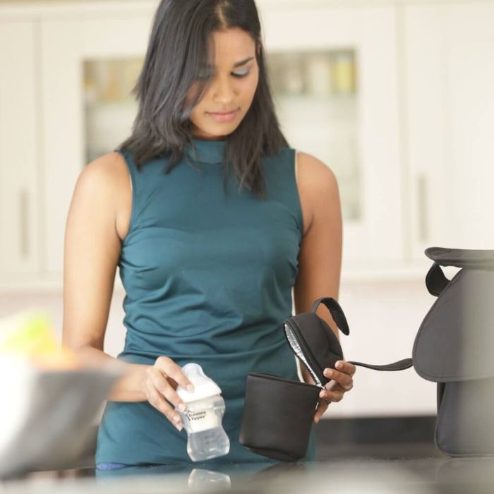 Woman placing baby bottle into insulated bottle bag